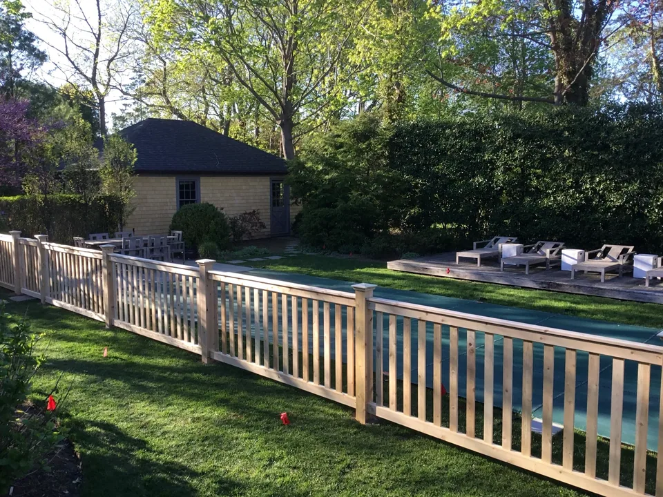 Custom white cedar fence across a landscaped Bellport Village backyard