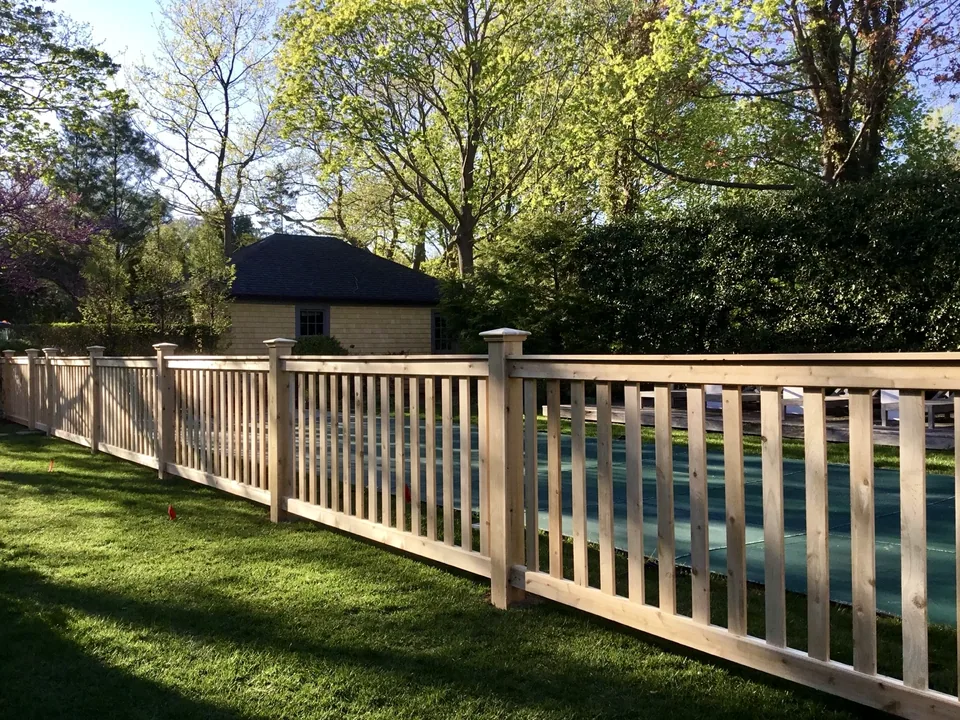 Long run of custom white cedar fencing in a landscaped Bellport Village backyard