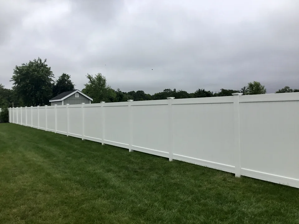 Long straight run of white PVC privacy fence across a lawn in Wading River, New York